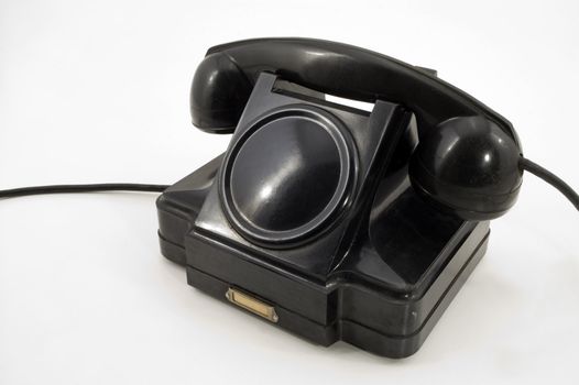 Old-fashioned black telephone receiver with cord on white background