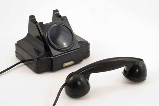 Old-fashioned black telephone receiver with cord on white background.