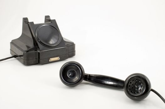 Old-fashioned black telephone receiver with cord on white background.