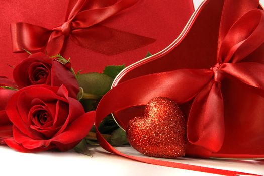 Chocolate boxes with red satin ribbons and roses on white background