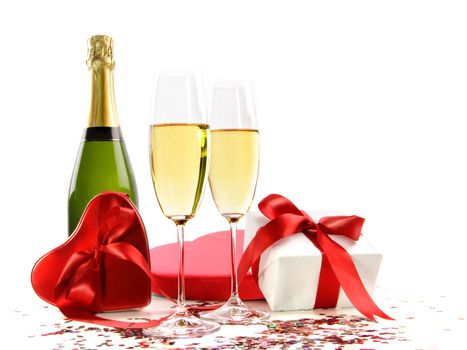 Glasses of champagne with bottle and gifts on white