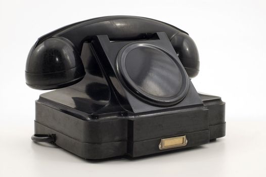 Old-fashioned black telephone receiver with cord on white background.