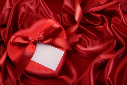 Box of chocolate with red ribbon on satin