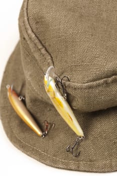 A fisherman's hat with lures attached shot against white background with soft shadow