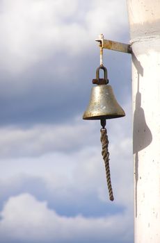 Ferruginous ship bell on a background cloudy sky 