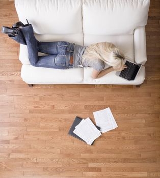 High angle view of a woman using her laptop with papers scattered about. Vertical shot.