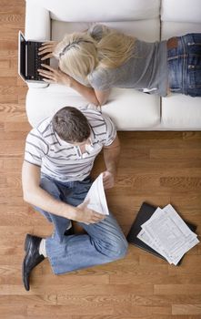 High angle view of a young couple with a laptop and paperwork. Vertical shot.