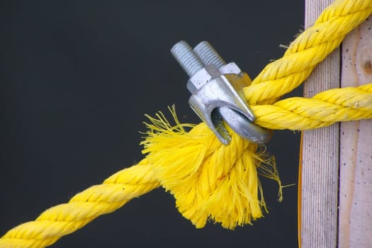 a yellow rope for a tie-down is clamped by metallic fastening