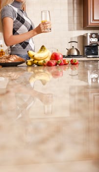 Young woman in kitchen holding a glass of orange juice. Vertical shot.