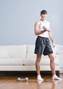 Man using arm weight in his living room as another lies on the floor next to him. Vertical format.