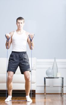 Man standing and using resistance bands in his living room. Vertical format.