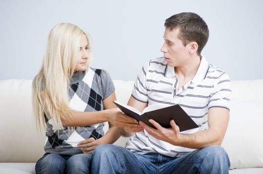 Attractive couple tussling over a book. Horizontal shot.