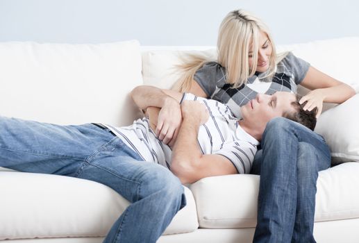 Couple relaxing on couch, with man lying with his head in the woman's lap. Horizontal format.