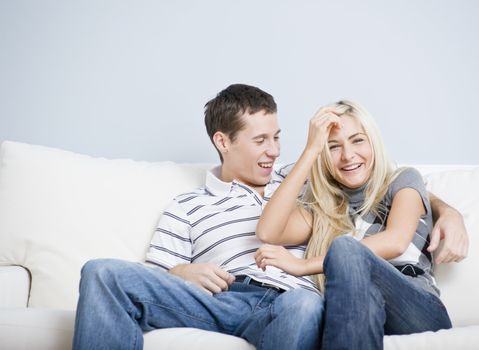 Cropped view of affectionate couple laughing and relaxing together on white couch. Horizontal format.