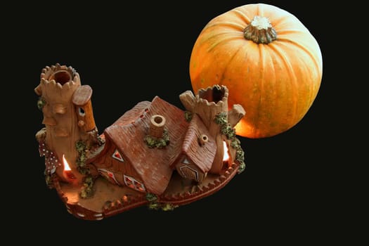 ceramic house with lightning windows near pumpkin