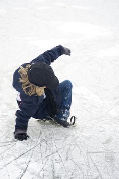 a young boy is falling on the ice, and loosing his ice-skate