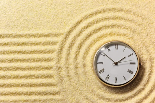 Old round watch on a surface of golden sand