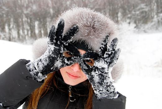 beautiful girl in winter clothing holds her hands like sunglasses