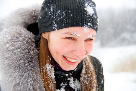 laughing girl with snow on her face staying in a winter woods