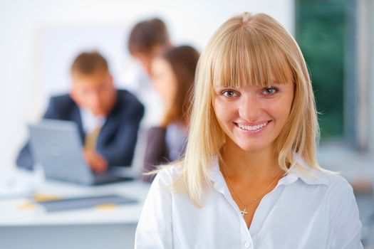 Young happy business woman with her working friend at the background