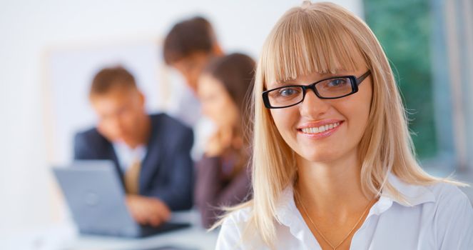 Smiling business woman with her working friends at the background