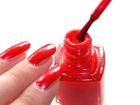 woman's nails with manicure and vial of red color nail polish