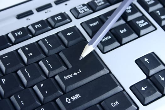 The pencil lying on a key Enter the computer keyboard