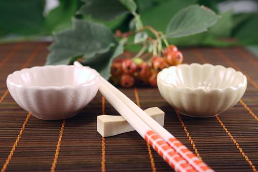 Chopsticks with two drinking bowl on a bamboo napkin