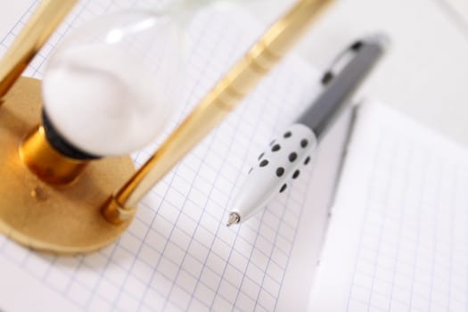 Part of a sand-glass on a notebook with the pen removed close up