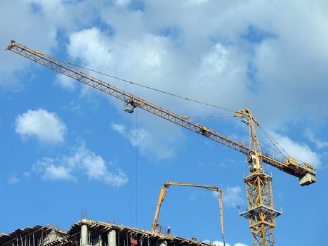 Yellow tower crane on a construction site on a background of the sky with clouds, (look similar images in my portfolio)