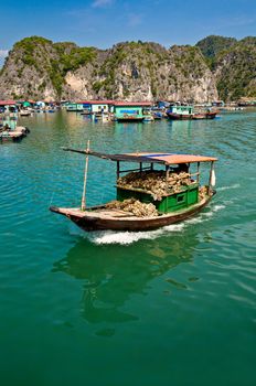 Wooden boat near one of the many fish farms located at Ha Long Bay.