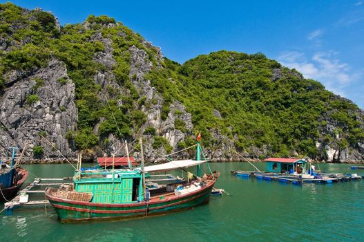 Wooden boat near one of the many fish farms located at Ha Long Bay.