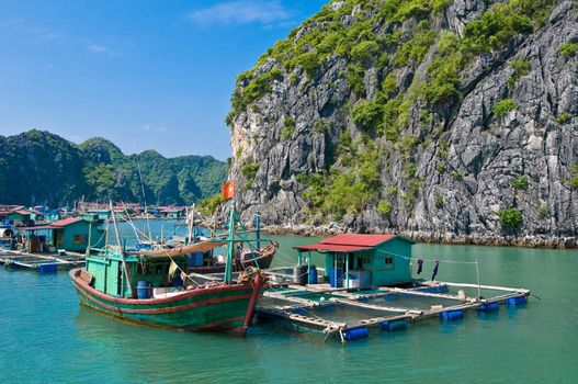 Wooden boat near one of the many fish farms located at Ha Long Bay.
