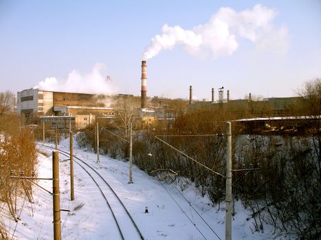 Rail bed coated by a snow near a metallurgical plant with smoking funnels, (look similar images in my portfolio)