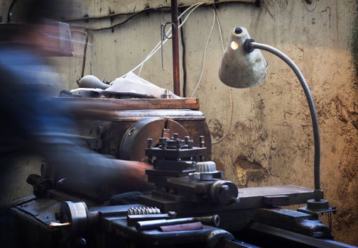 Worker and old gear in vintage workshop