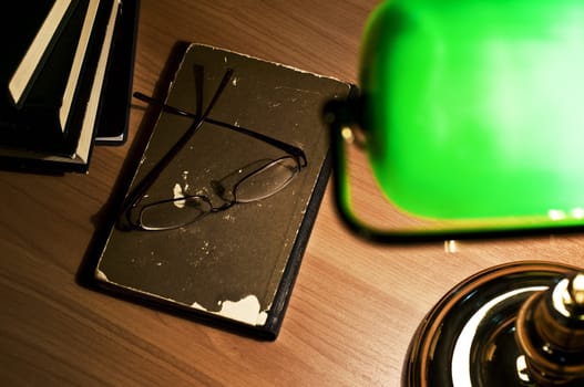 Electric green table lamp and opened book, glasses