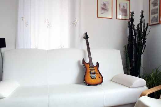 Nice living room with guitar standing on white leather sofa