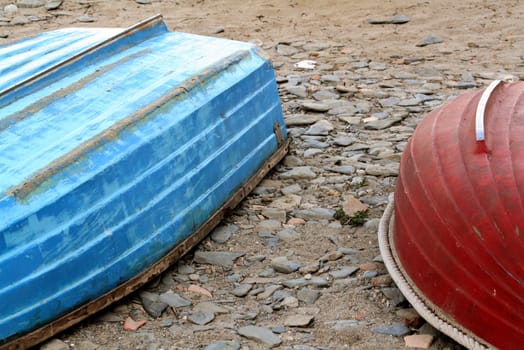 a red and a blue little boats resting at the beach
