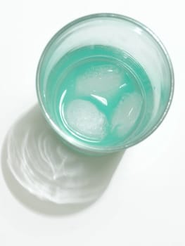 green drink in glass with pieces of ice