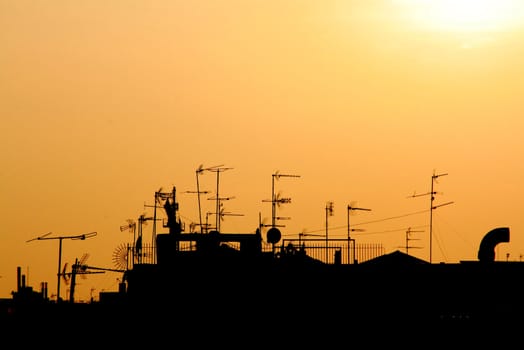 city skyline with roofs, anthennas, railings, at the sunset time
