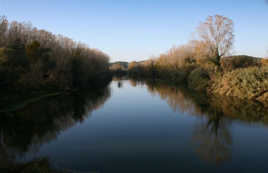 Landscape of a river on autumn, beautiful reflections and colors. Clean blue sky
