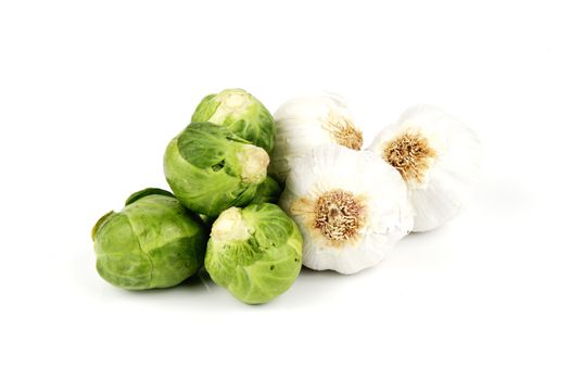 White raw garlic bulbs with green raw sprouts on a reflective white background