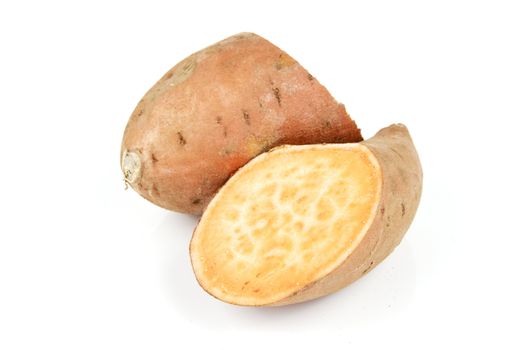 Raw sweet potato cut in half on a reflective white background