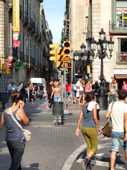 People walking in Barcelona. Traffic lights, streets and buildings.