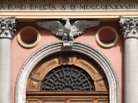 Beautiful wooden door with an eagle sculpture and decorative columns. Old building in Rome.