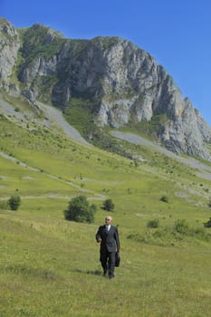 Businessman walking in a mountaineous area.