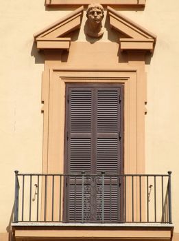 Beautiful window on an orange wall of a historic building in Rome.