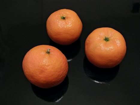 Three orange mandarines against the black background    