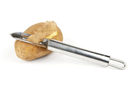 Small brown raw potato with chrome peeler on a reflective white background