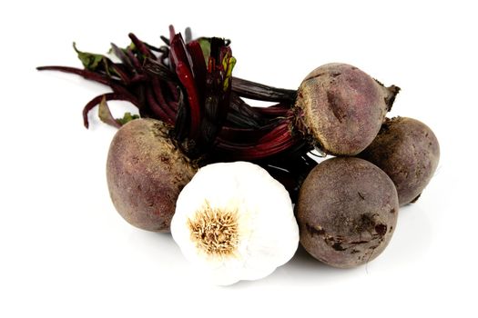 Bunch of raw red beetroot on a reflective white background